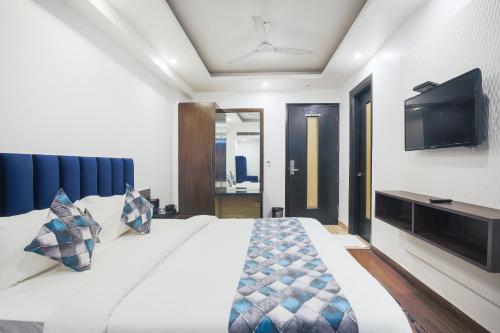 a bedroom with a bed with a tv on the wall at Hotel Uppal International in New Delhi