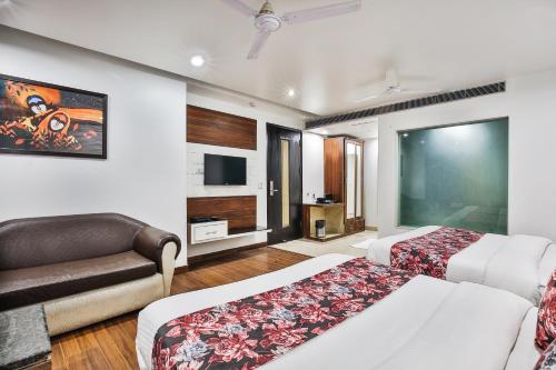 a hotel room with two beds and a couch at Hotel Uppal International in New Delhi