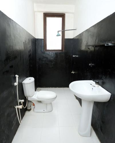 a black and white bathroom with a toilet and a sink at Yarra BUNKZ Kandy in Kandy
