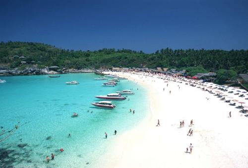 a group of people on a beach with boats in the water at patong v hotel in Patong Beach