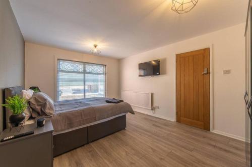 a bedroom with a large bed and a large window at Modern Fully Renovated 4 Bedroom in Cwm-brân