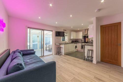 a living room with a purple couch and a kitchen at Modern Fully Renovated 4 Bedroom in Cwm-brân