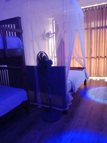 a bedroom with two beds and a room with a fan at Ella glory inn in Ella