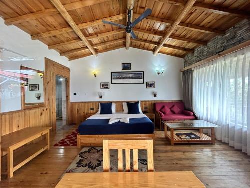 a bedroom with a bed and a ceiling fan at Kasar Himalaya Holiday Resort, Binsar Rd in Almora