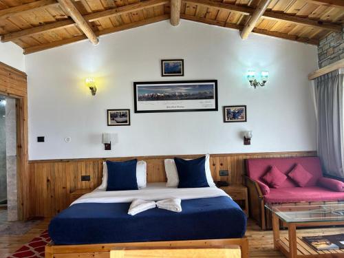 a bedroom with a bed and a red couch at Kasar Himalaya Holiday Resort, Binsar Rd in Almora