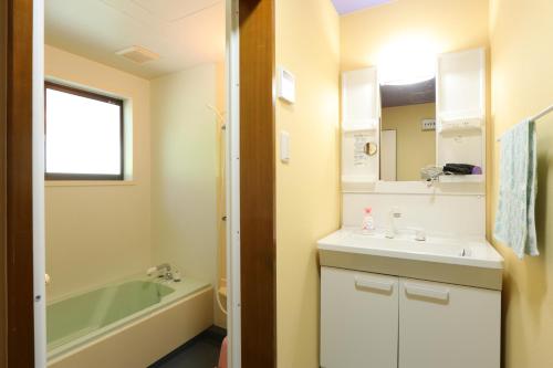 a bathroom with a sink and a bath tub at なごみの里 in Shionoe