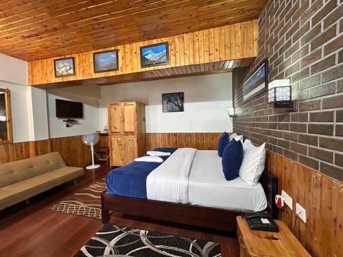a bedroom with a bed and a brick wall at Kasar Himalaya Holiday Resort, Binsar Rd in Almora