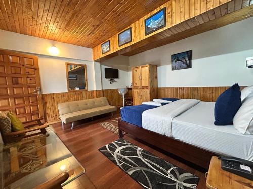 a bedroom with a bed and a couch in a room at Kasar Himalaya Holiday Resort, Binsar Rd in Almora