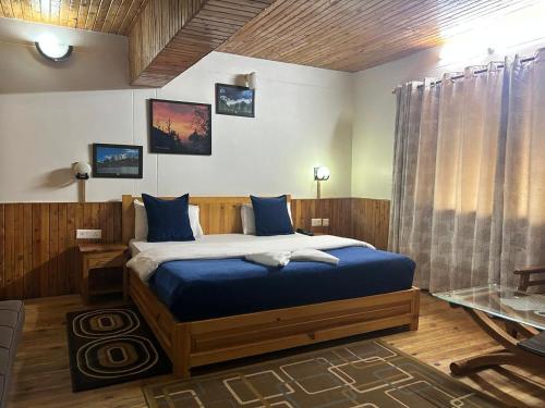 a bedroom with a large bed with blue sheets at Kasar Himalaya Holiday Resort, Binsar Rd in Almora