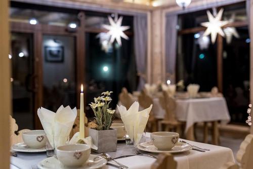 a table with plates and cups and a candle on it at Willa Litworówka III Wellness&SPA in Poronin