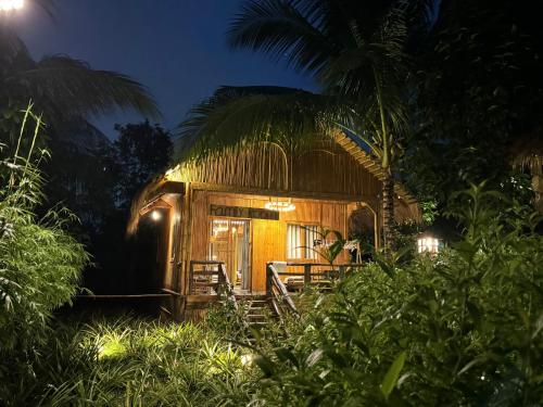 a man sitting in front of a small house at night at Bamboo Eco Village in Can Tho