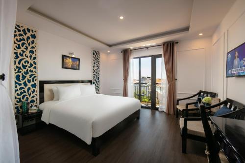 a bedroom with a white bed and a balcony at Hoi An Golden Holiday Villa in Hoi An
