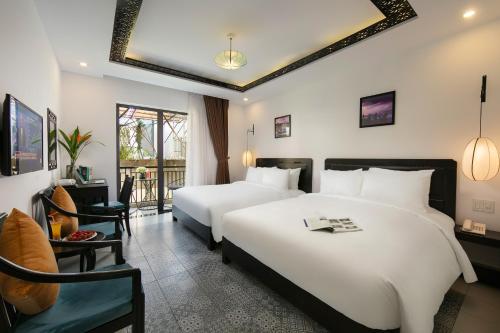 a hotel room with two beds and a chair at Hoi An Golden Holiday Villa in Hoi An