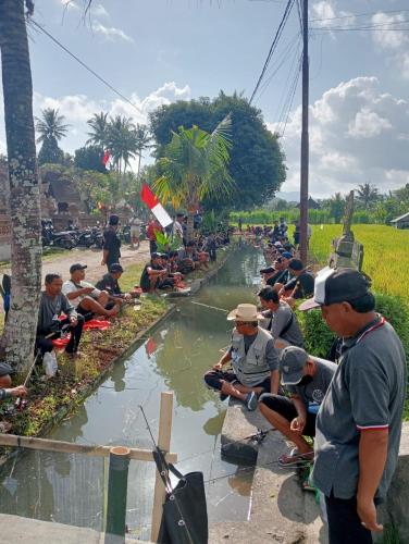 a group of people sitting next to a river at Bali Bakas House II in Banjarangkan
