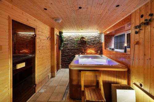 a bathroom with a tub and a stone wall at Penzion Pulčiny 43 in Pulčín