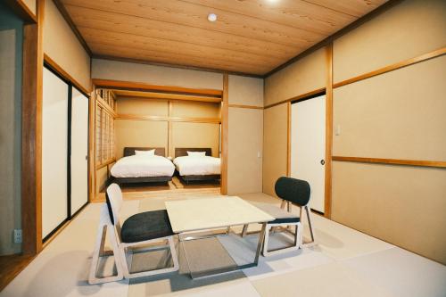 a room with two beds and a table and chairs at SATOYAMA STAY Tono-machi in Furukawachō