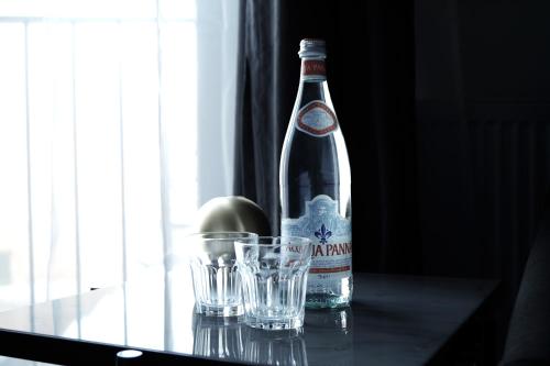 a bottle of alcohol and two glasses on a table at Hotel Bella Italia in Sønderborg