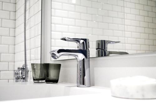 a bathroom sink with two faucets and a mirror at Hotel Bella Italia in Sønderborg