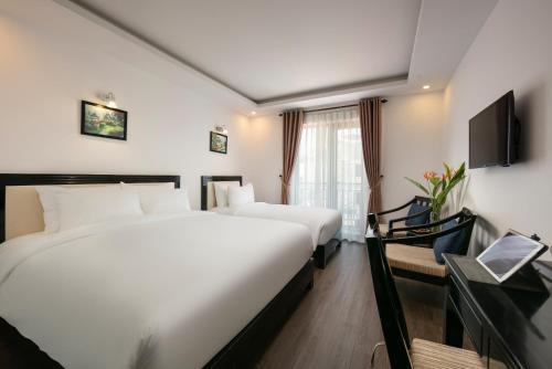 a hotel room with two beds and a tv at Hoi An Golden Holiday Villa in Hoi An