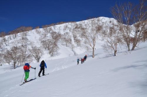 a group of people skiing down a snow covered slope at Hakuba Hospitality Inn YUKINOSO in Hakuba