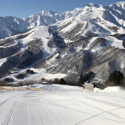 a snow covered mountain with a road in the foreground at Hakuba Hospitality Inn YUKINOSO in Hakuba