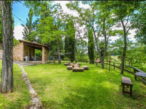 a park with benches and a building in the grass at Agriturismo La Moraia in Poggibonsi