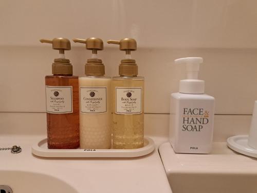 four bottles of hand soap sitting on a bathroom sink at Chisun Hotel Hamamatsucho in Tokyo