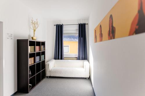 a living room with a chair and a book shelf at Hotel Wirtshaus Römerhof in Leibnitz