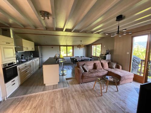 Il comprend un grand salon avec un canapé et une cuisine. dans l'établissement Chalet les brimbelles, à Le Tholy