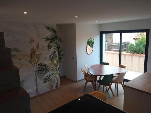 une salle à manger avec une table et une fresque murale. dans l'établissement Villa année 2024 Bord de mer 6 pers, à Sainte-Marie-Plage