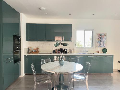 une cuisine avec des placards verts et une table avec des chaises dans l'établissement Villa mitoyenne de standing proche de toutes commodités à Ghisonaccia, à Ghisonaccia
