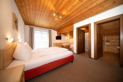 a bedroom with a large bed with a wooden ceiling at Pension Mozart in Wagrain