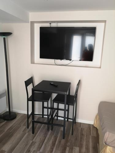 Cette chambre comprend une table, des chaises et une télévision murale. dans l'établissement Maison papa 2, à Nice
