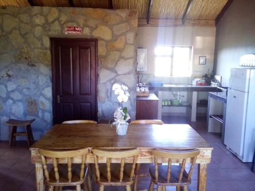 cocina con mesa de madera y sillas y cocina con nevera en Kampala Farm, en Bonnievale