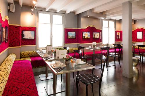 a restaurant with red furniture and tables and chairs at Hotel Design Sorbonne in Paris