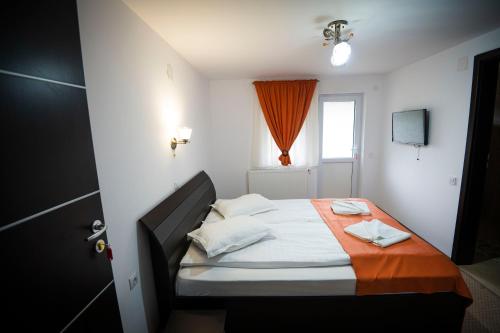 una piccola camera da letto con un letto con una coperta arancione di Roua Muntelui a Moieciu de Sus