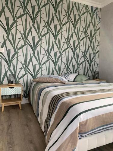 une chambre avec un lit avec un papier peint vert et blanc dans l'établissement Appartement T3 labellisé 3 étoiles, à Aurillac