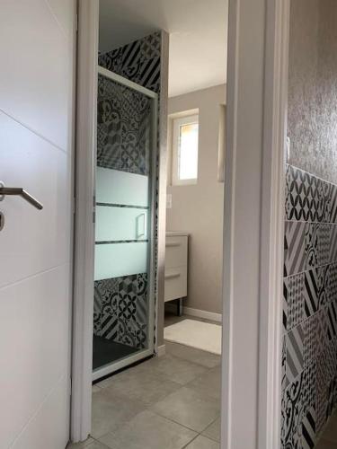 La salle de bains est pourvue d'un placard en verre avec un miroir. dans l'établissement Appartement T3 labellisé 3 étoiles, à Aurillac