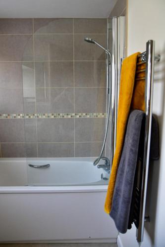 a bathroom with a shower and a tub with towels at Cosy cottage in Bridport centre in Bridport