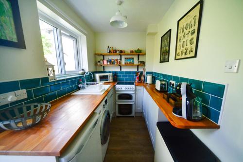 a kitchen with blue tiled walls and a wooden counter top at Cosy cottage in Bridport centre in Bridport