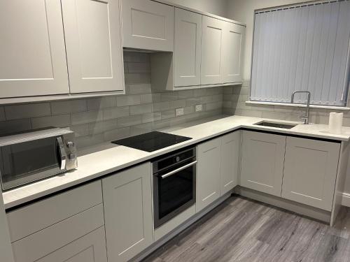 a kitchen with white cabinets and a stove top oven at Beachfront Apartment 3 Bedrooms Sleeps 7 - Gateway to the Lake District - Newly Refurbished in Morecambe