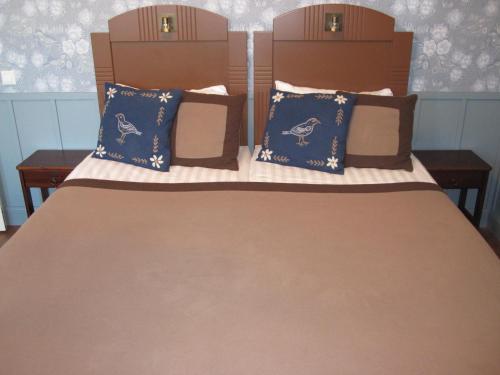 a bed with blue and brown pillows on it at Hotelli-Ravintola Alma in Seinäjoki
