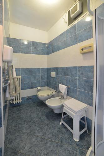 a blue tiled bathroom with two toilets and a sink at Hotel Rosalia in Bordighera