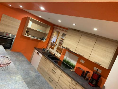 a kitchen with wooden cabinets and an orange wall at Les Cigognes de Rosheim in Rosheim