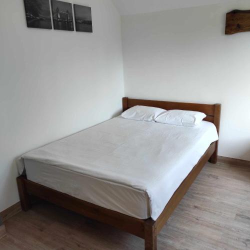 a bed with white sheets and pillows in a room at Poilsio namelis Plateliai in Plateliai