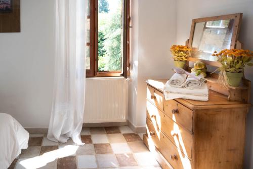 - une chambre avec une commode avec un miroir et une fenêtre dans l'établissement Domaine de la Clédette grand gîte, à Colognac
