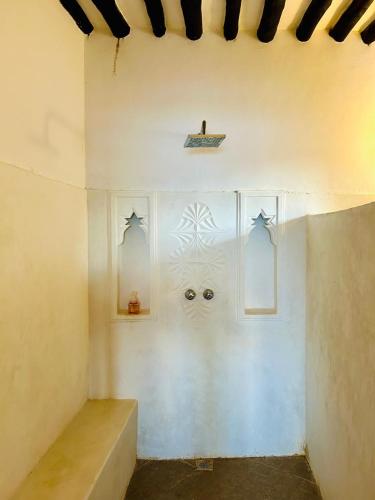 a room with a white wall with two windows with eyes at Shela Bahari in Shela