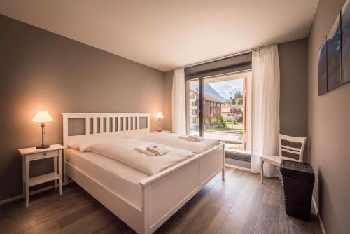 a bedroom with a white bed and a large window at Independance First in Interlaken