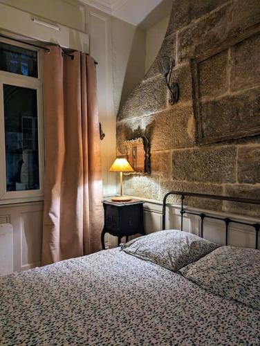 une chambre avec un lit et un mur en pierre dans l'établissement L'appartement du voisin d'Hugo, à Besançon