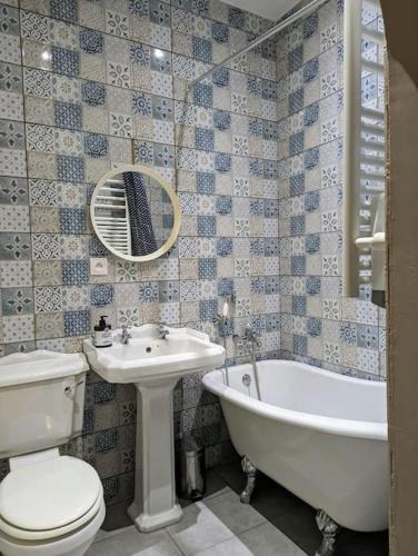 une salle de bain avec toilettes, baignoire et lavabo dans l'établissement L'appartement du voisin d'Hugo, à Besançon